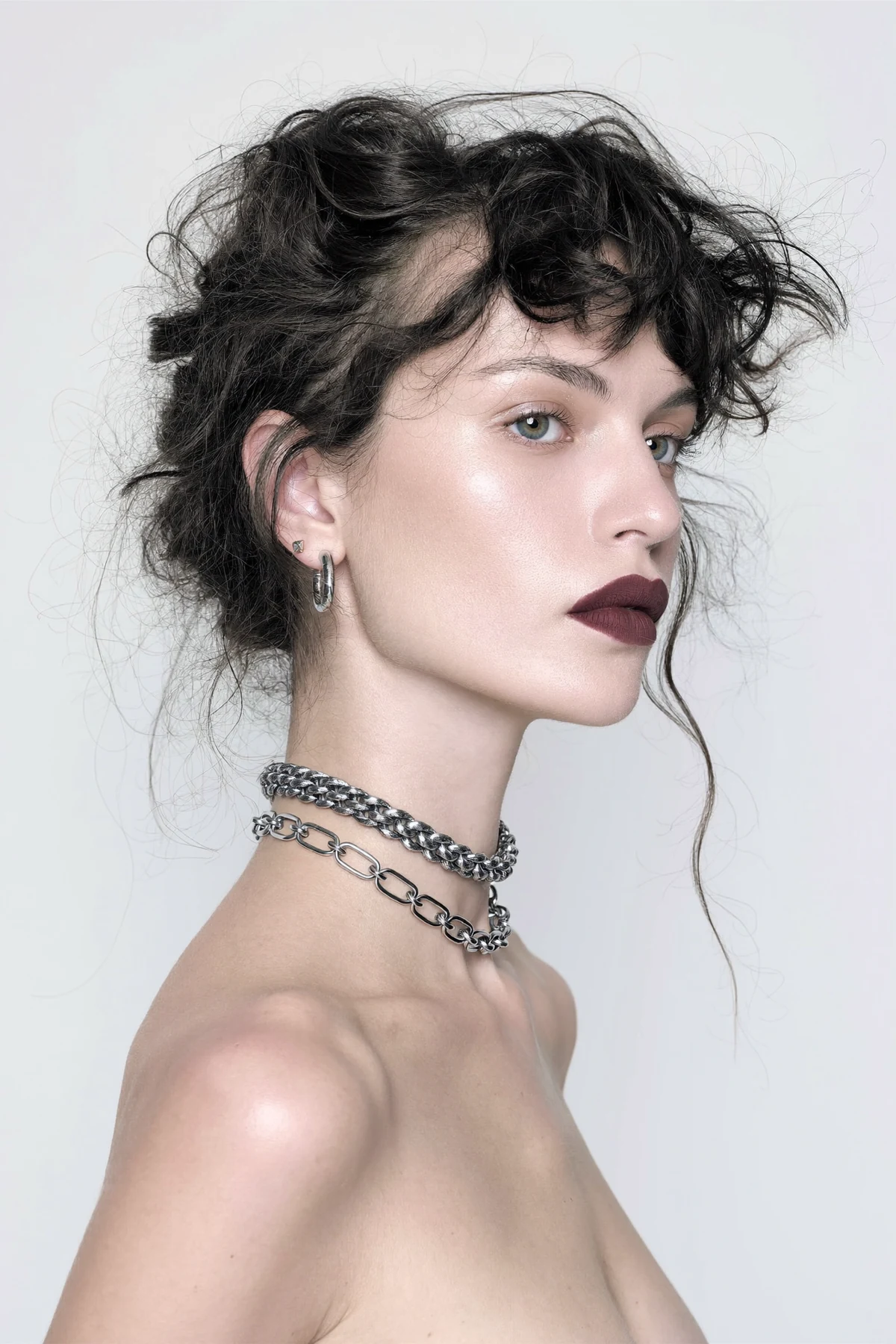 Short-haired model wearing layered silver necklaces